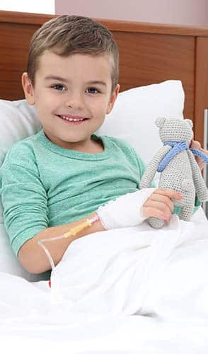 Little child with intravenous drip and toy in hospital bed