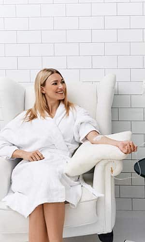 Maintenance and restoration of human immune system with vitamin IV infusion therapy. Beautiful woman with her boyfriend in modern wellness center during intravenous vitamin therapy.